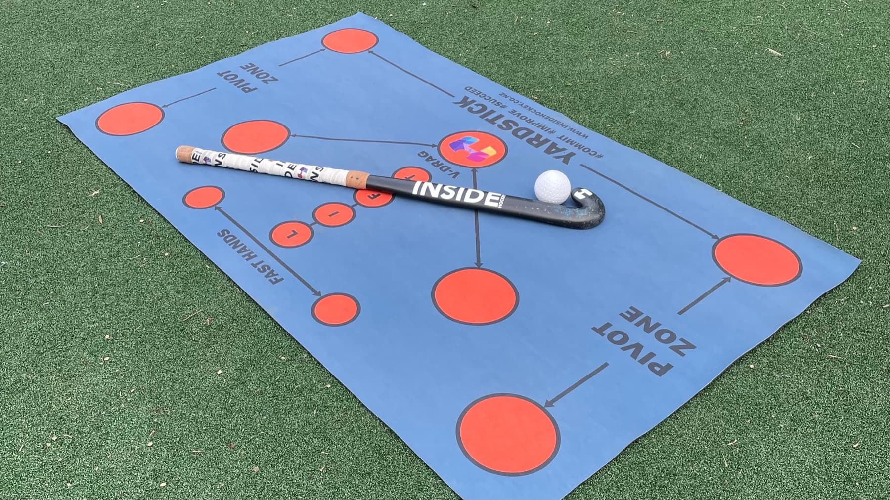 Inside Hockey Skills Mat with a hockey stick and ball on turf.